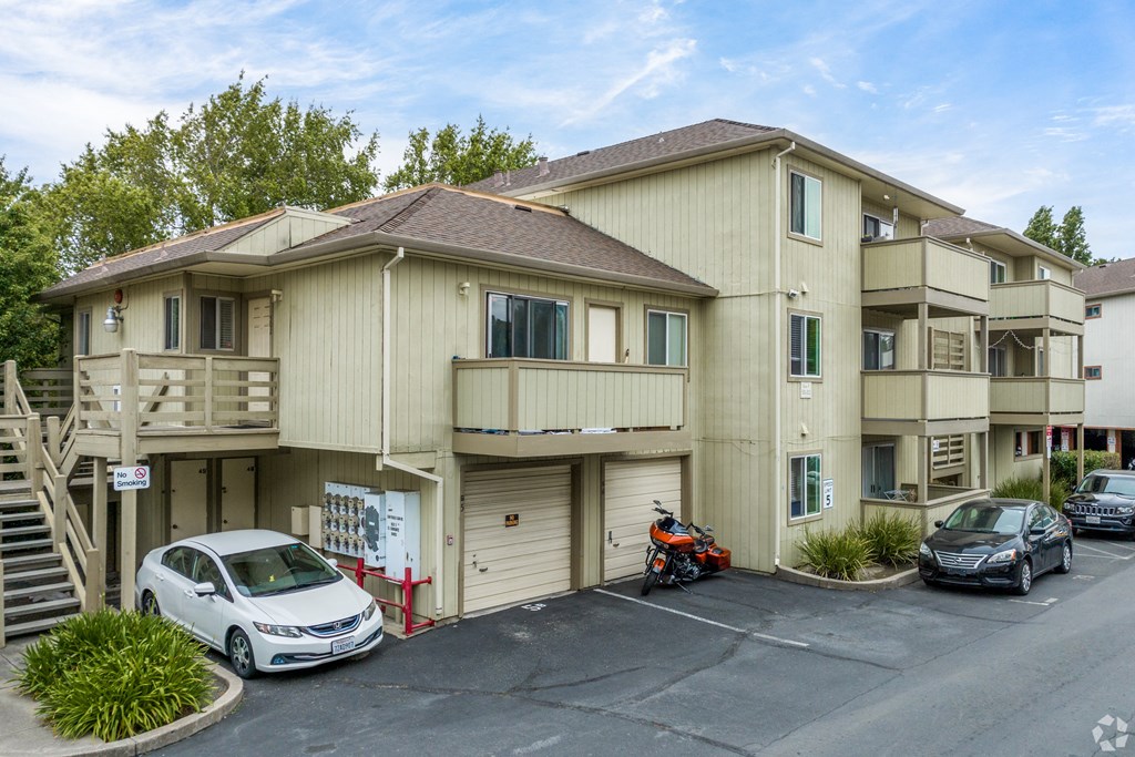 a beige apartment building with cars parked in front of it