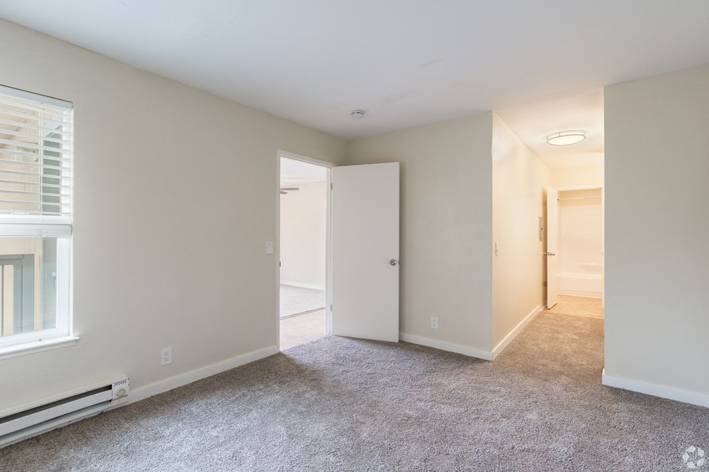 an empty living room with white walls and a door to a bathroom