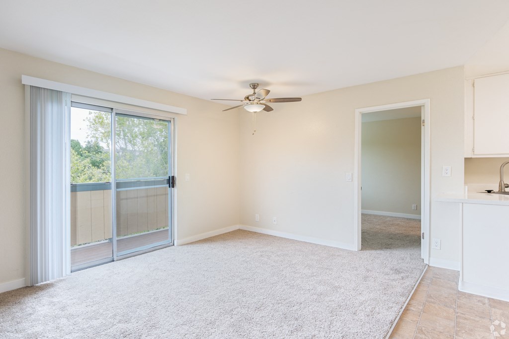 an empty living room with a ceiling fan and sliding glass doors