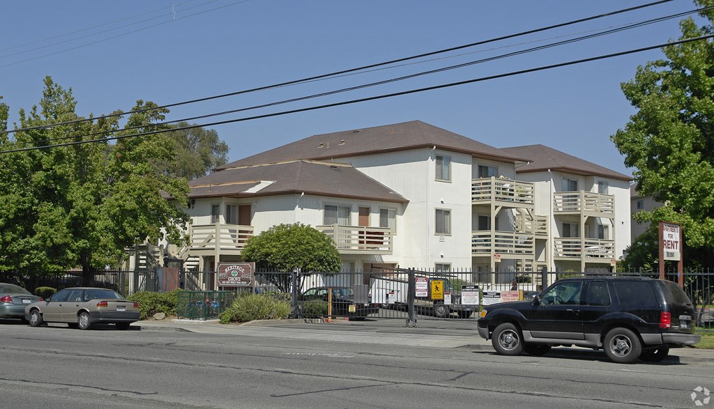 an apartment building on the corner of a street with cars