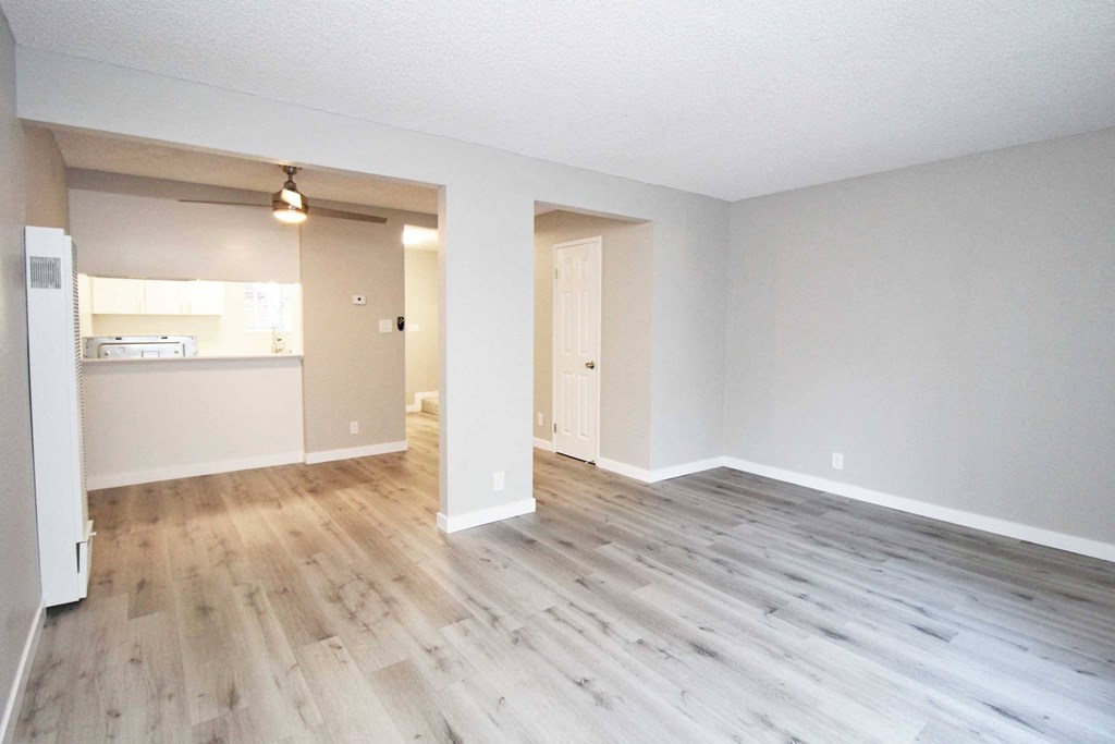 the living room and kitchen of an empty apartment with wood floors