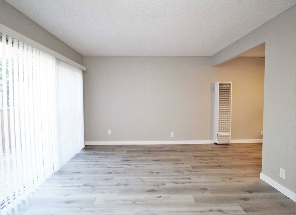 an empty living room with a large window and wood floors