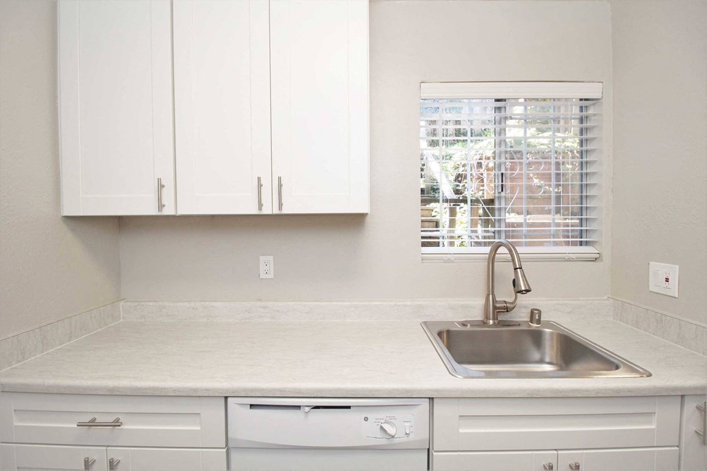 a kitchen with white cabinets and a sink and a window