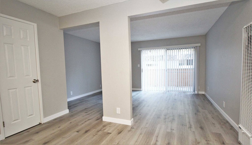 an empty living room with wood flooring and a window