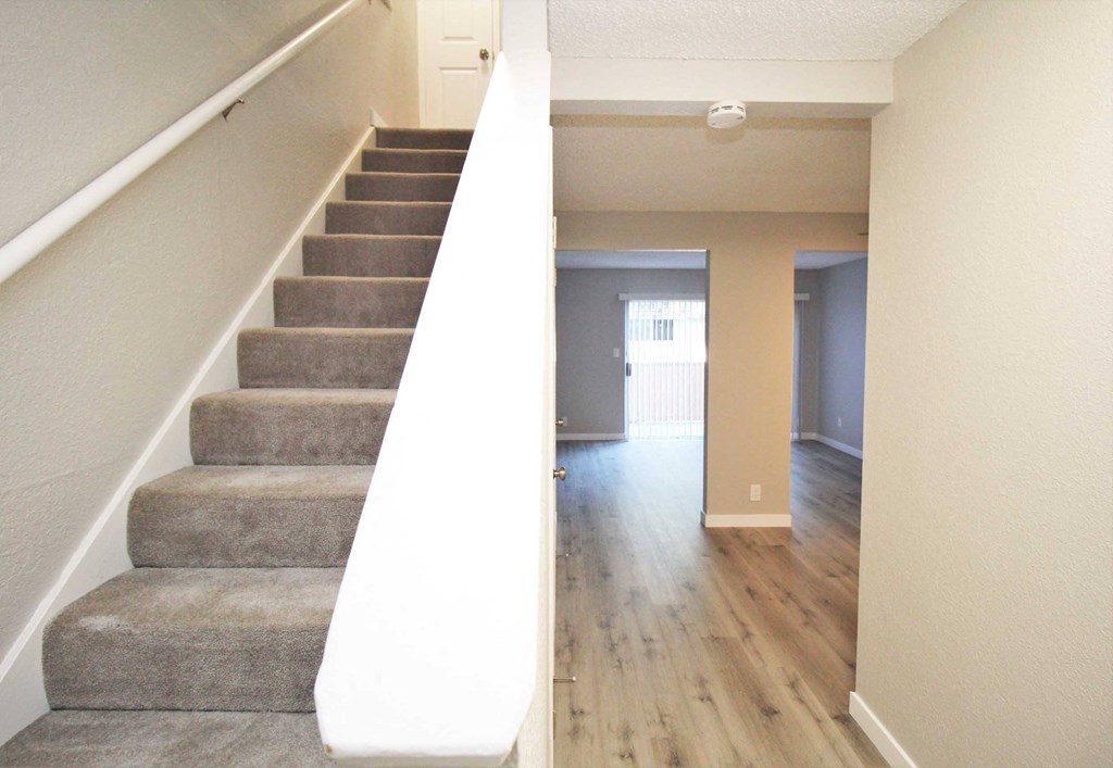 a view from the bottom of the stairs looking into the living room and dining room