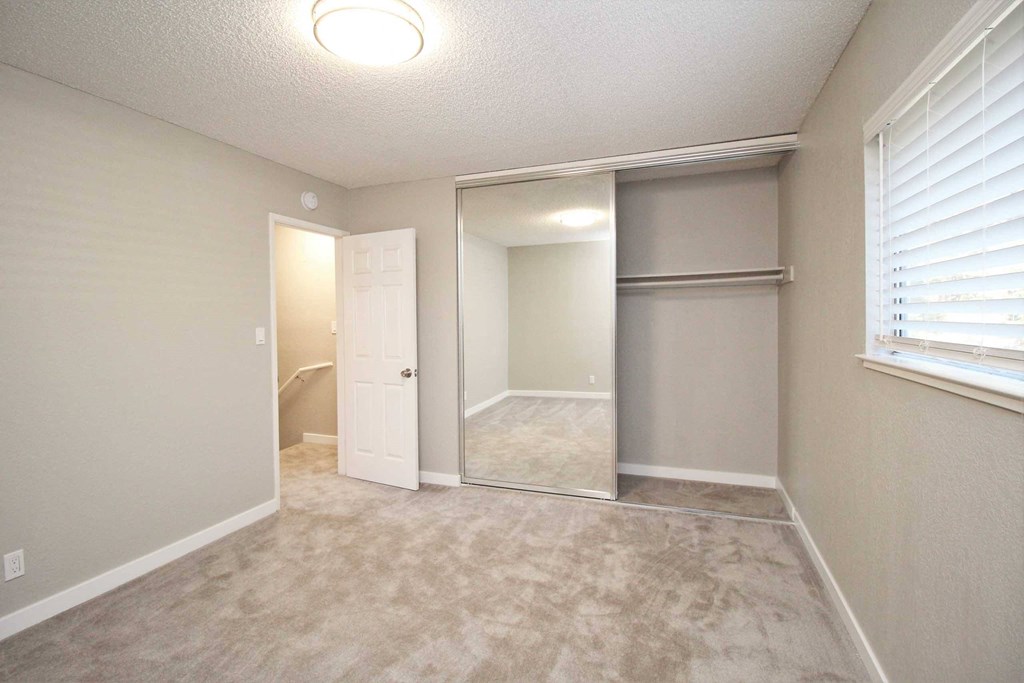 an empty bedroom with a closet and a door to a bathroom