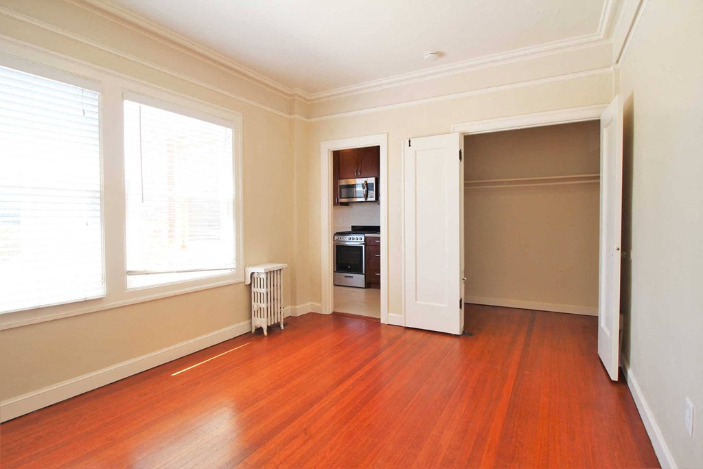 an empty living room with wood floors and a closet