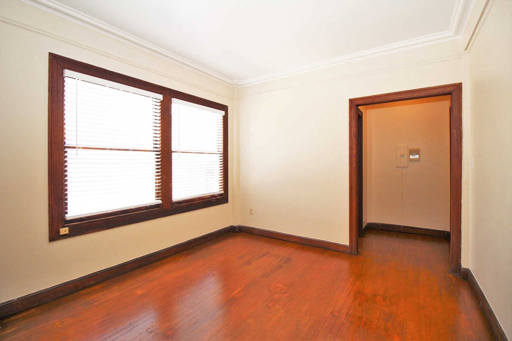 an empty living room with wood floors and a window and a door
