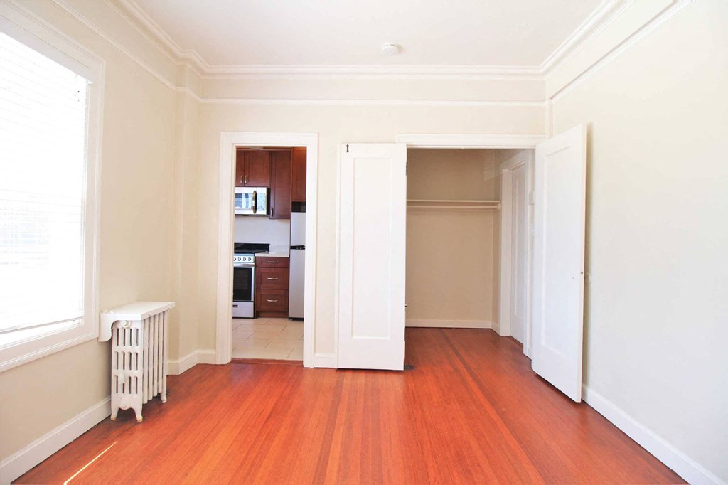 a living room with wood floors and a doorway into a kitchen