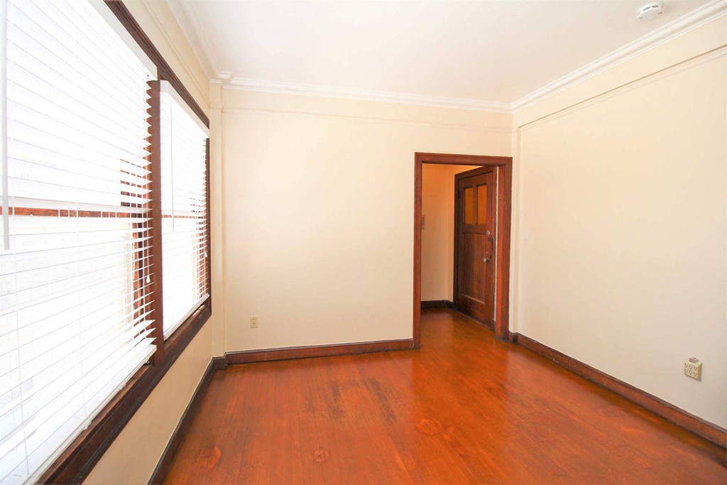 a empty living room with wood floors and a window