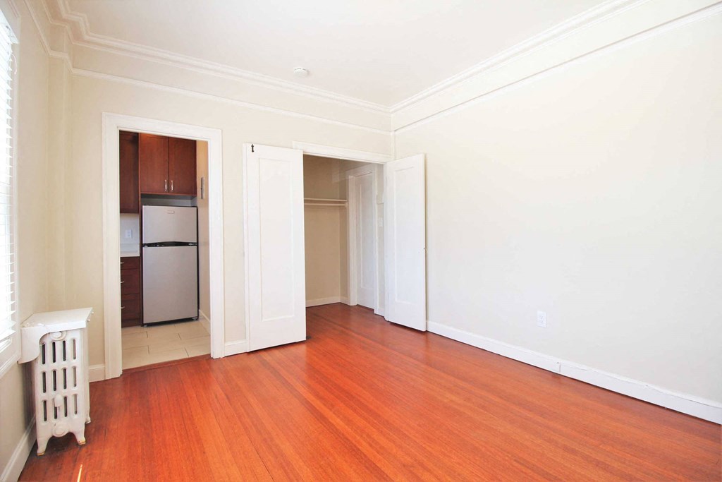 an empty living room with wood floors and white walls