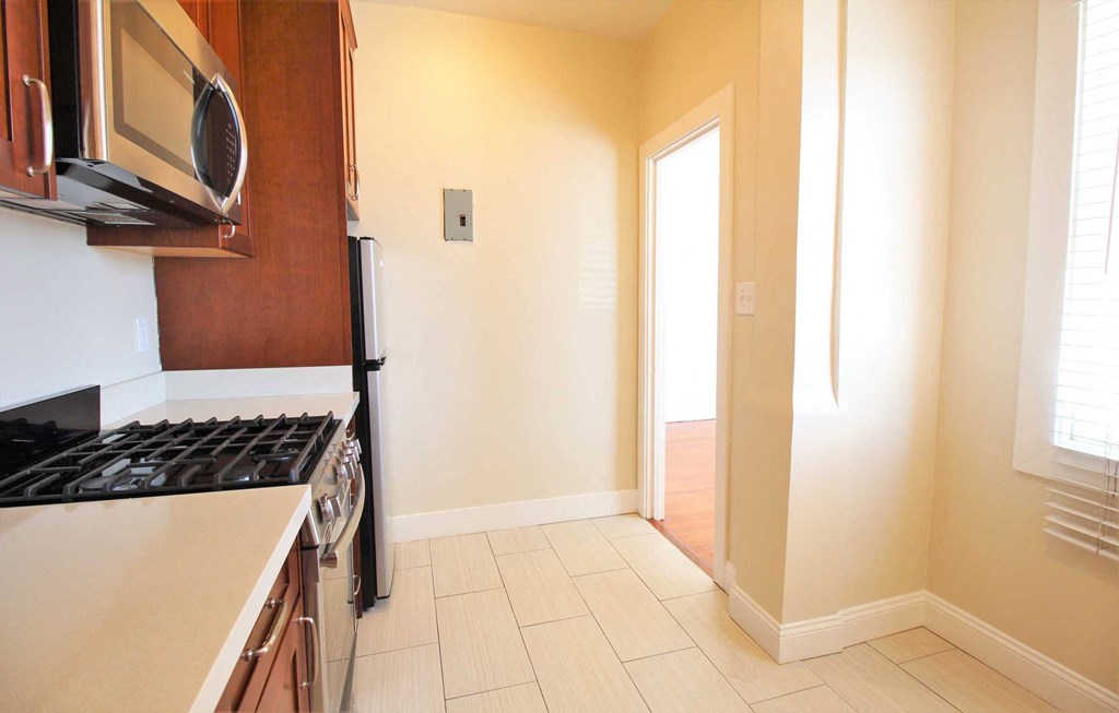 a kitchen with a stove and a microwave and a door to a hallway