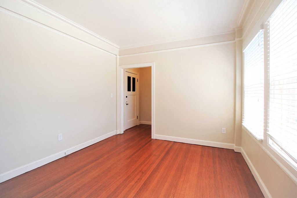 an empty living room with wood floors and white walls