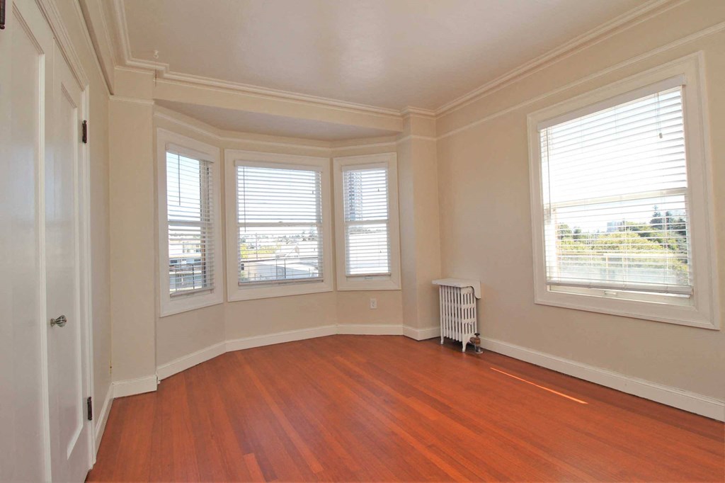 an empty living room with a wood floor and three windows