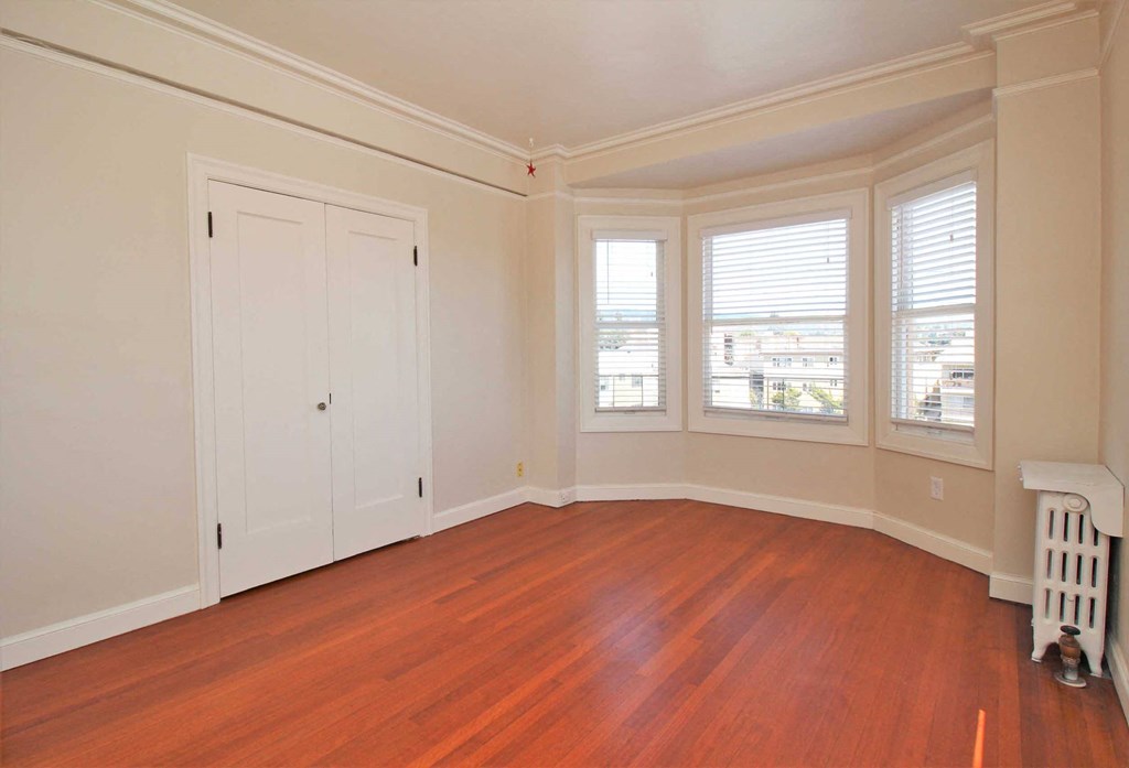 an empty living room with wood floors and white walls