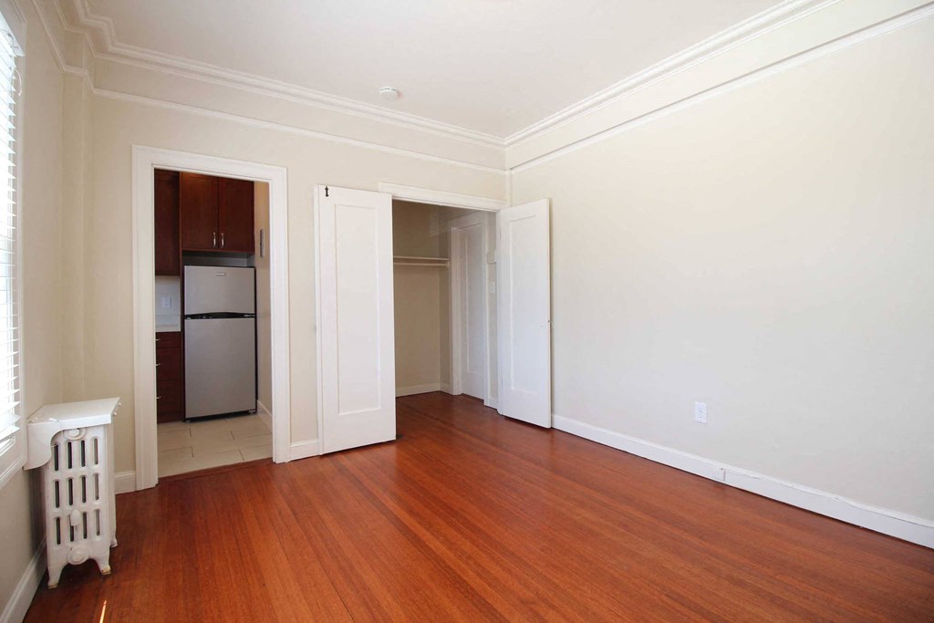 an empty living room with wood floors and white walls