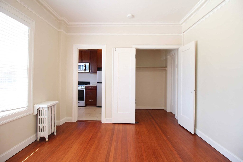 a living room with a wood floor and a doorway into a kitchen
