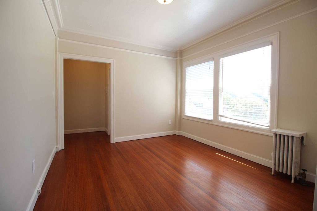 an empty room with wood floors and a window