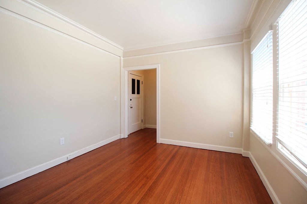 a living room with a hard wood floor and white walls