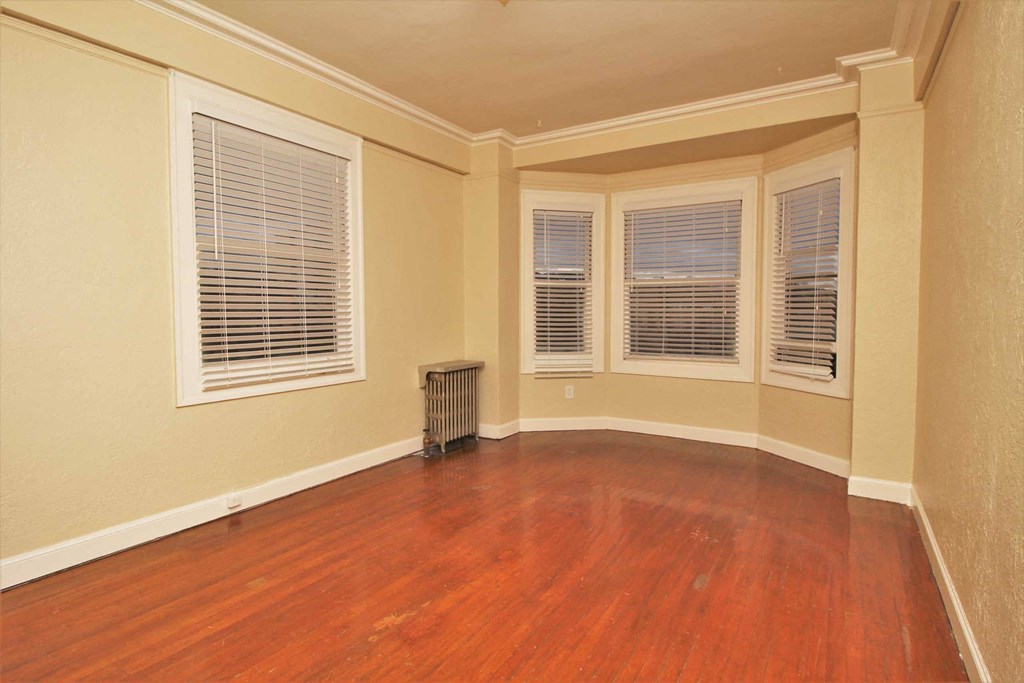 an empty living room with wood floors and windows