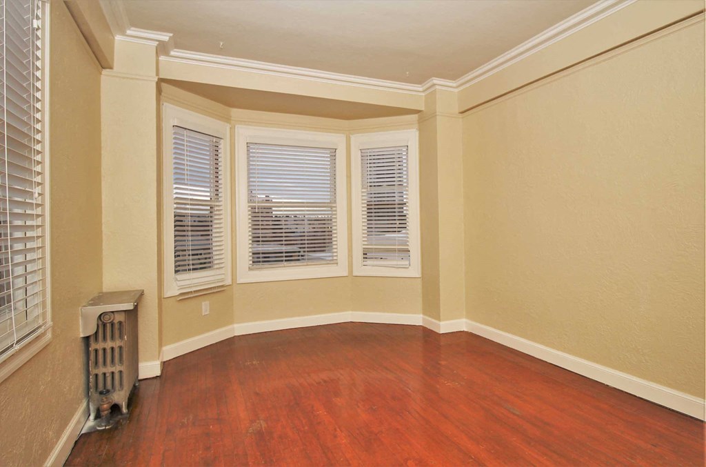 an empty living room with wood floors and windows