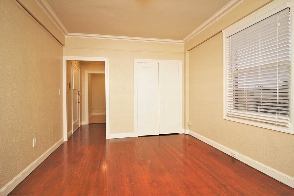 an empty living room with wood floors and a window