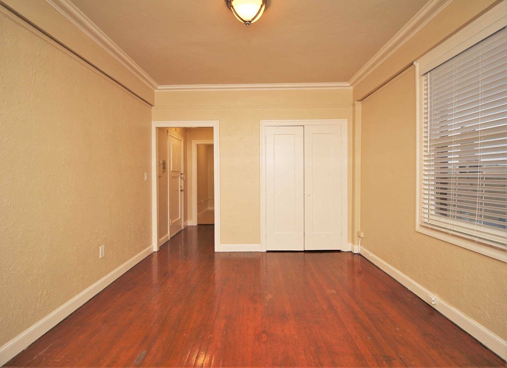 an empty living room with wood floors and a window