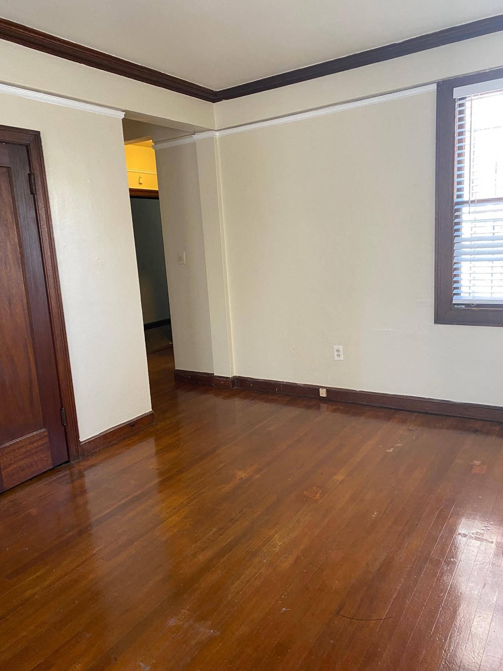 a living room with wood floors and white walls and a window