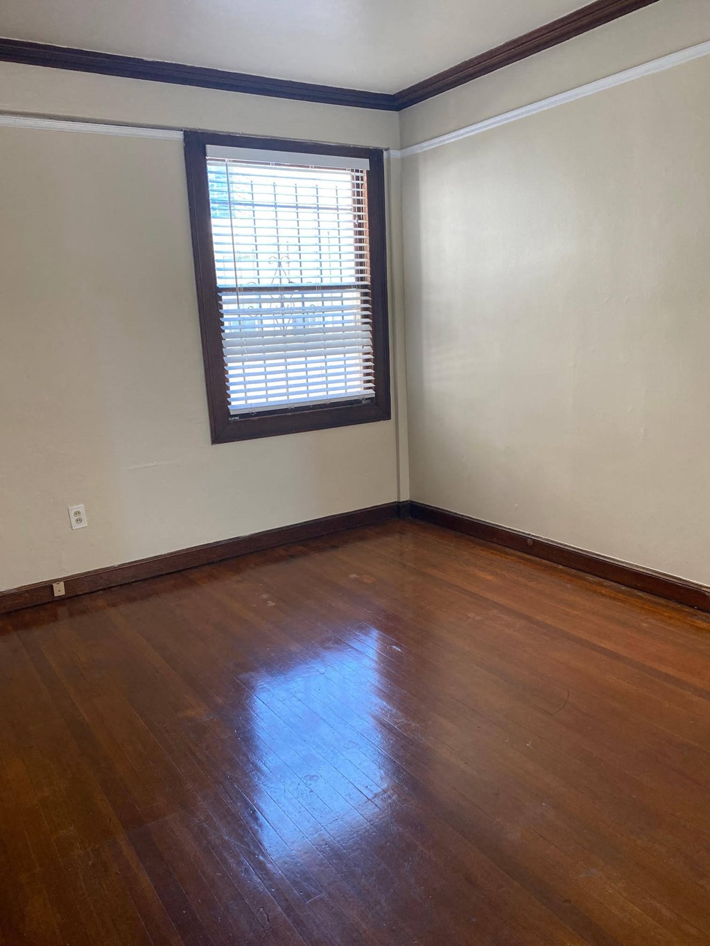 an empty room with wooden floors and a window