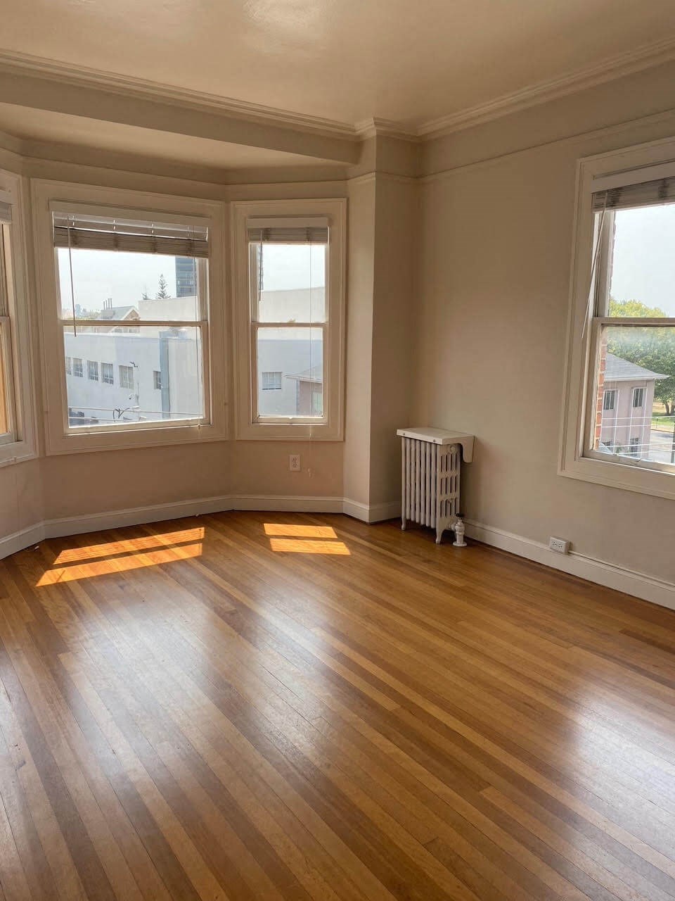 an empty living room with a wooden floor and three windows