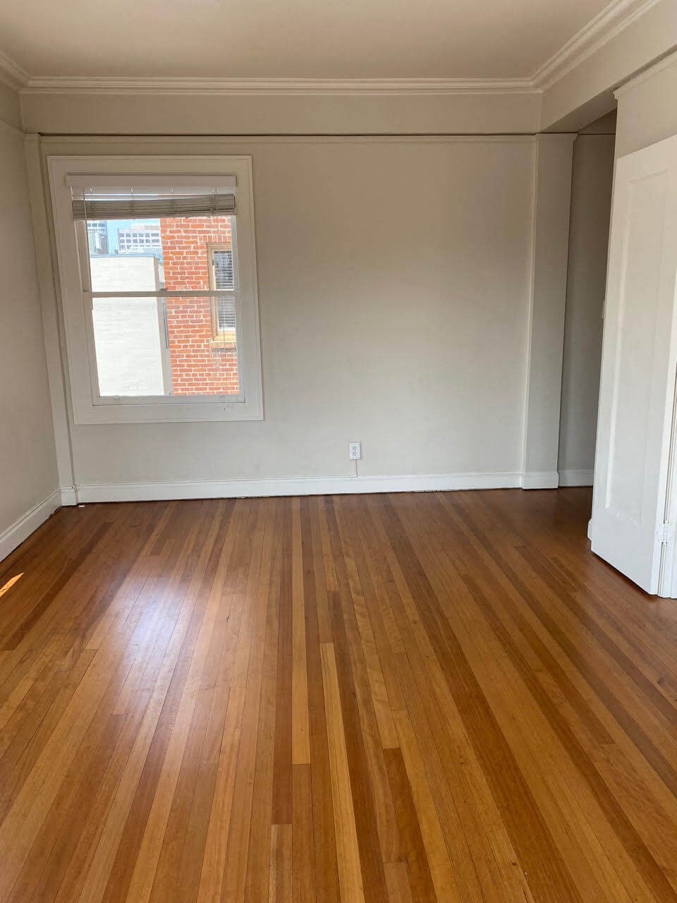 an empty living room with wood floors and a window
