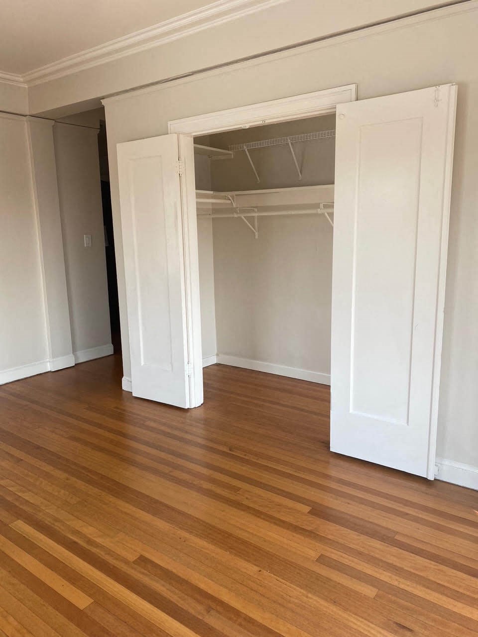 a living room with a hard wood floor and an open closet