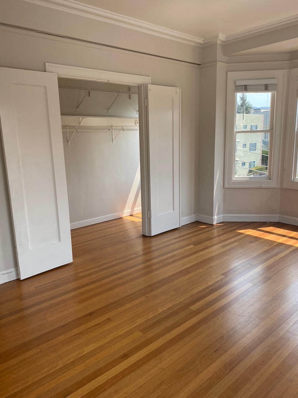 an empty living room with a hard wood floor and open doors