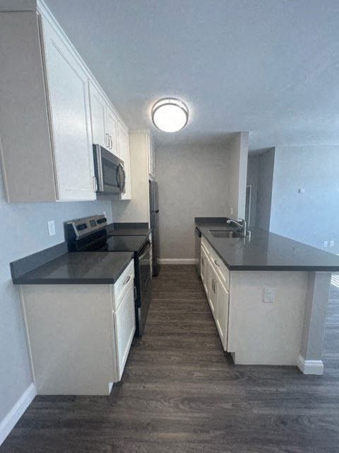 a kitchen with white cabinets and black counter tops