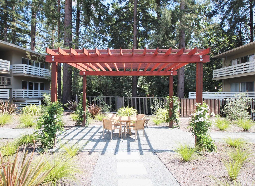a patio with a table and chairs under a wooden pergola