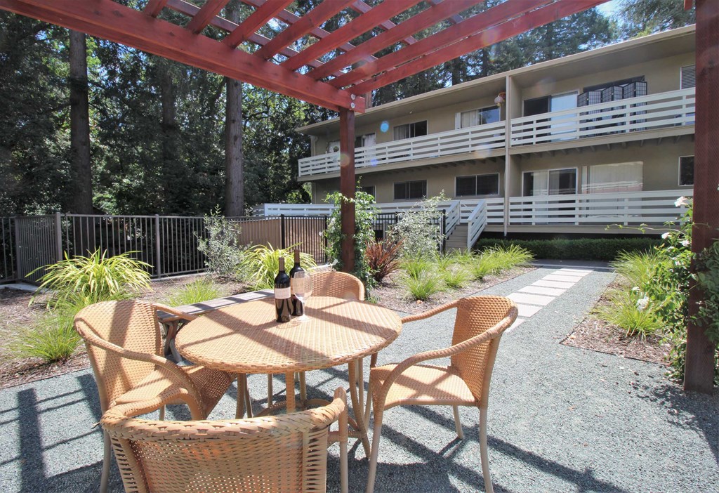 a patio with a table and chairs in front of a building