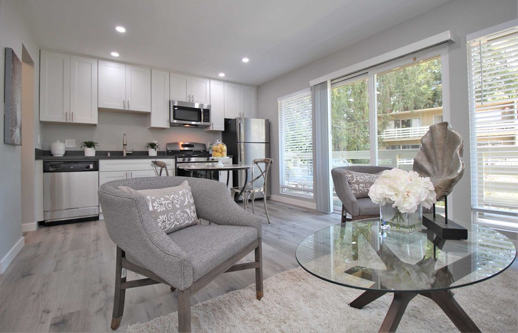 a living room and kitchen with a glass table and chairs