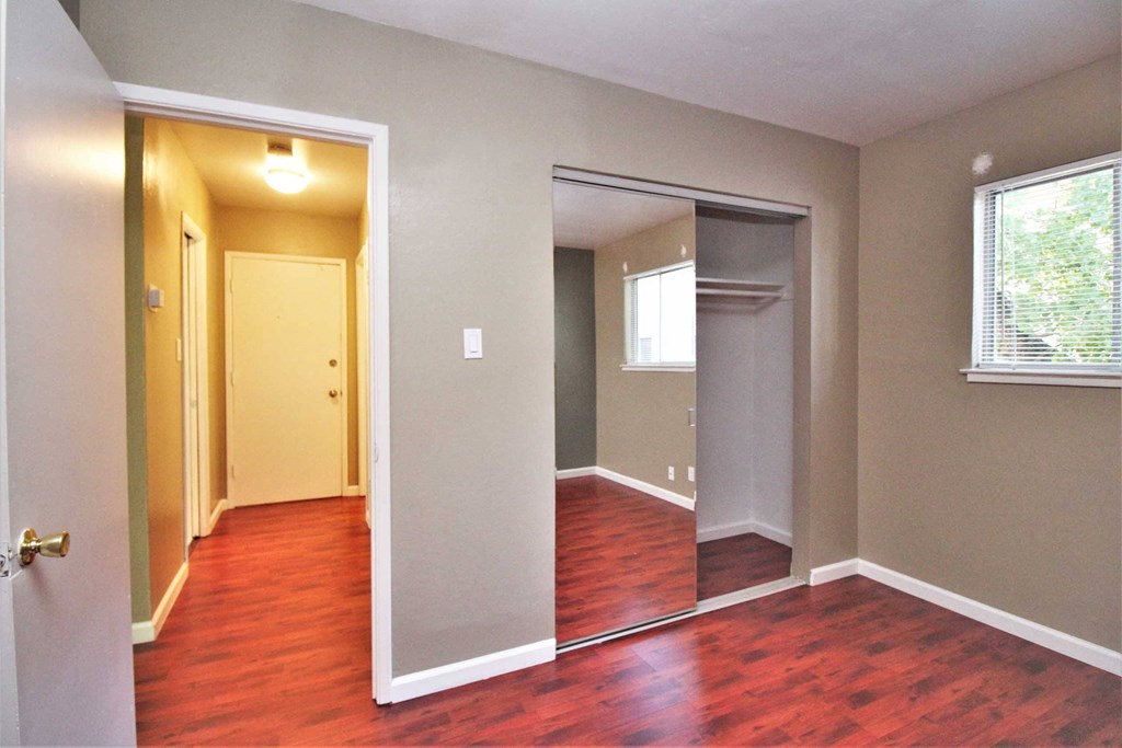 an empty living room with a hard wood floor and an open closet