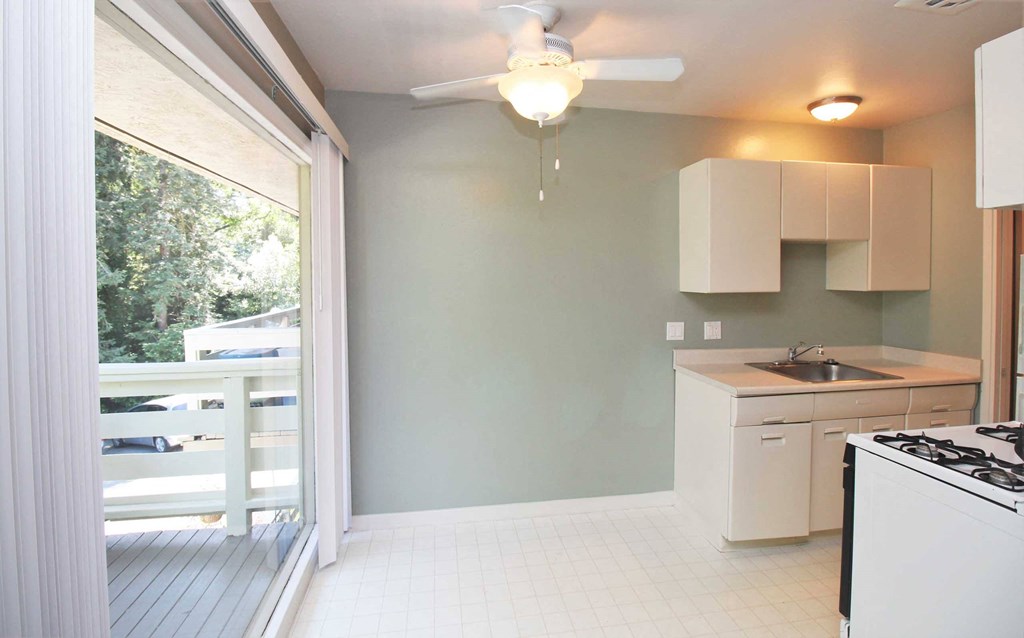 an empty kitchen with a sliding glass door to a balcony