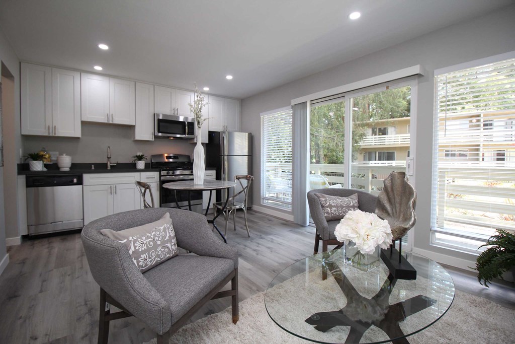 a living room and kitchen with a glass table and chairs