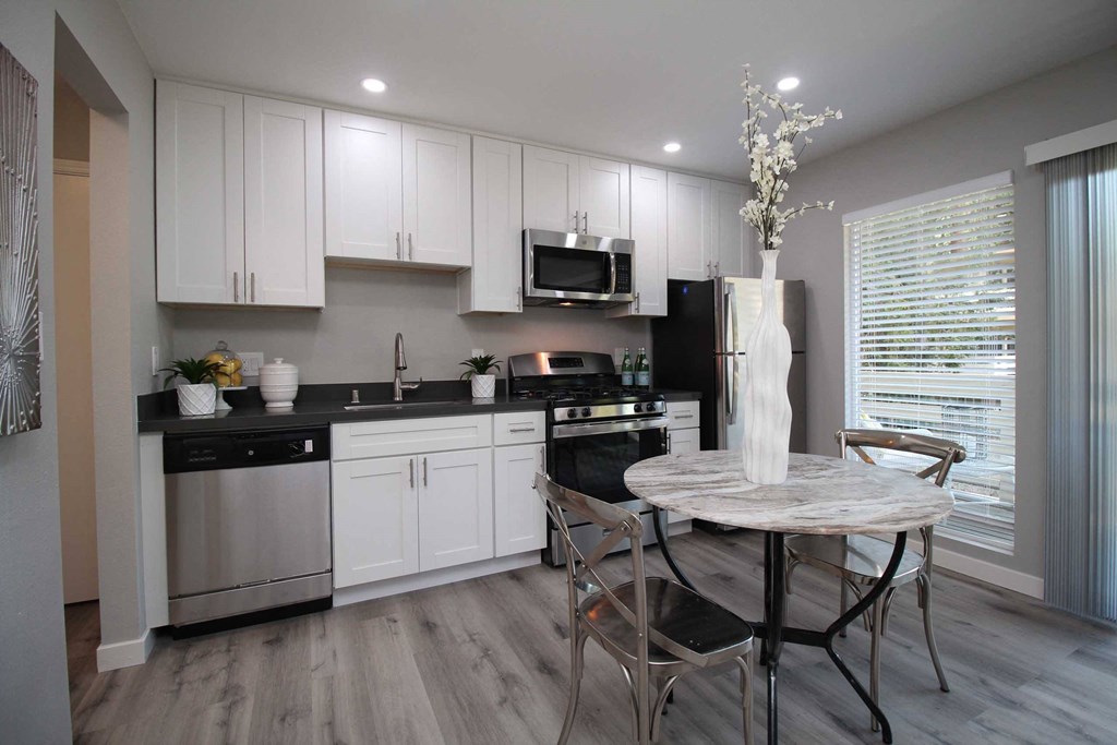 a kitchen with white cabinets and a table with chairs