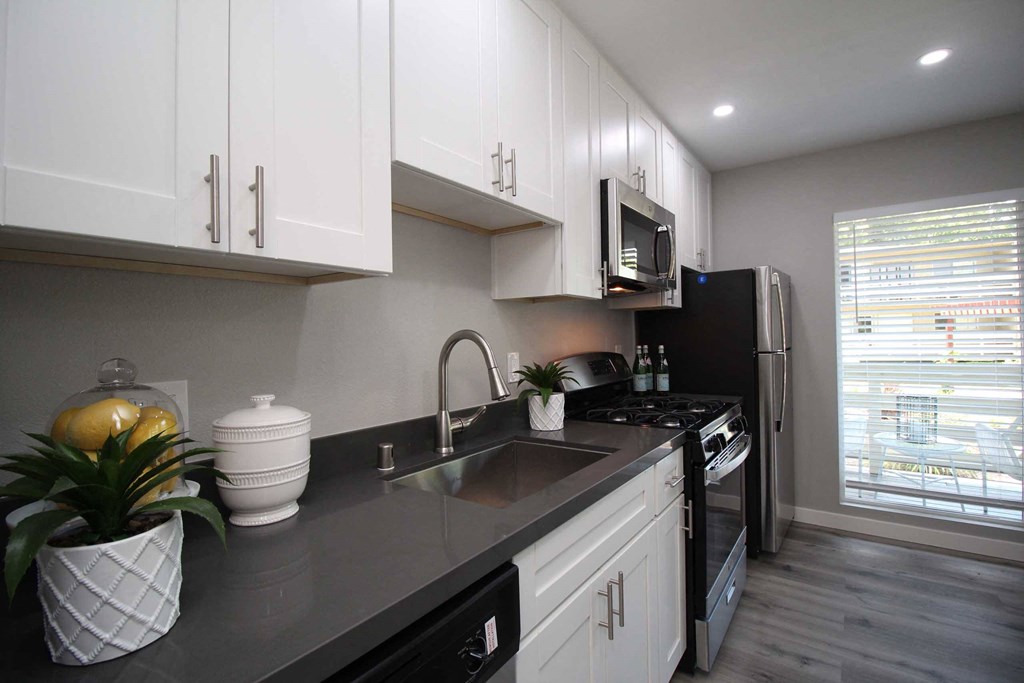 a kitchen with black counter tops and white cabinets