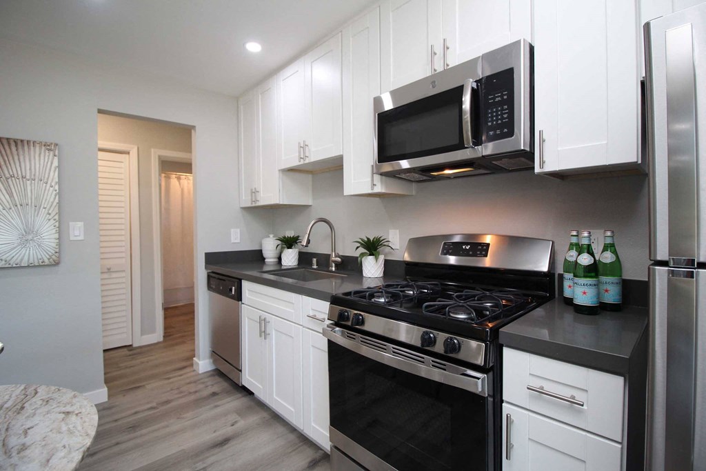 a kitchen with white cabinets and a stove and a microwave