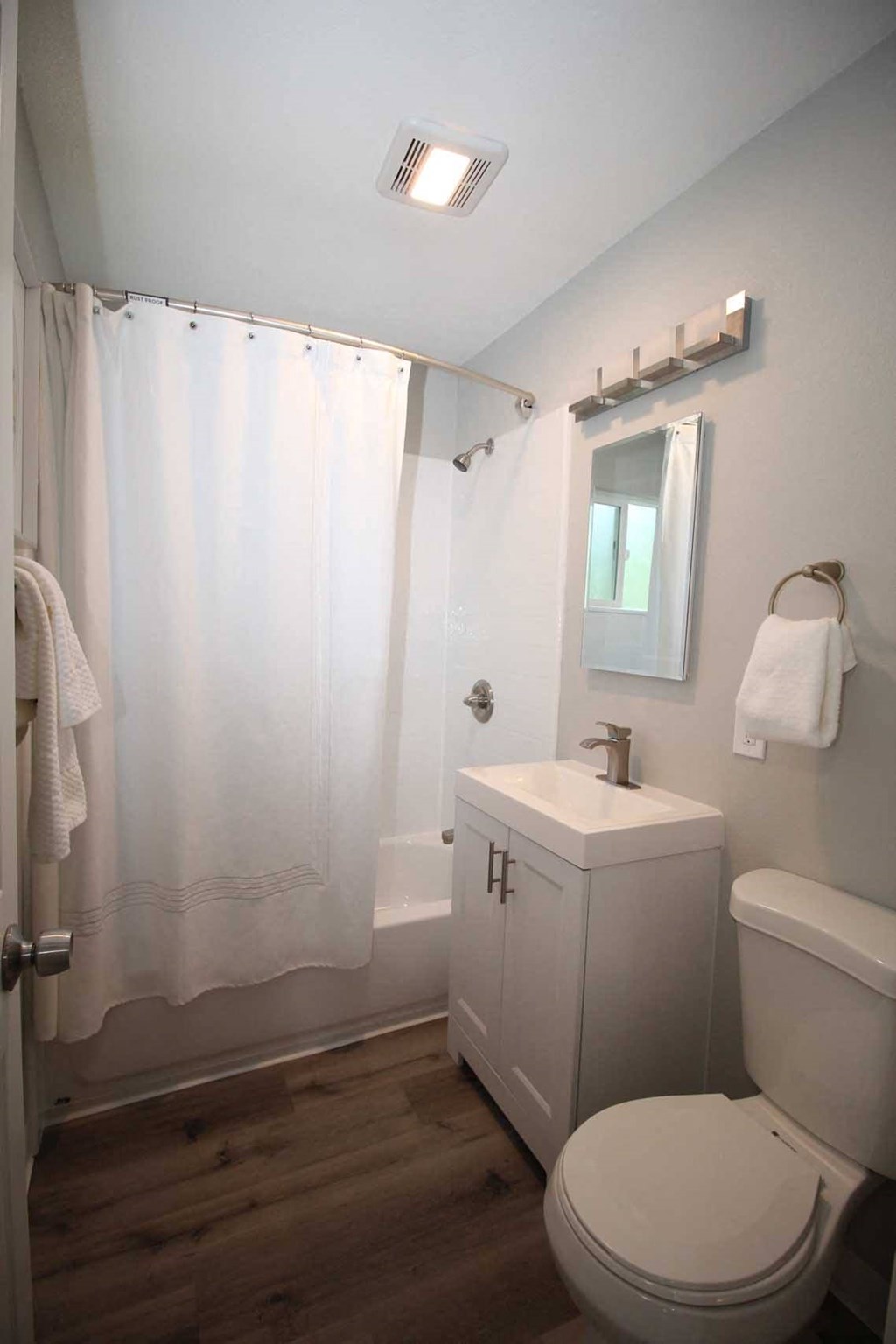 a white bathroom with a white shower curtain and a white toilet and sink