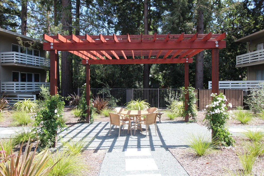 a patio with a table and chairs under a wooden pergola