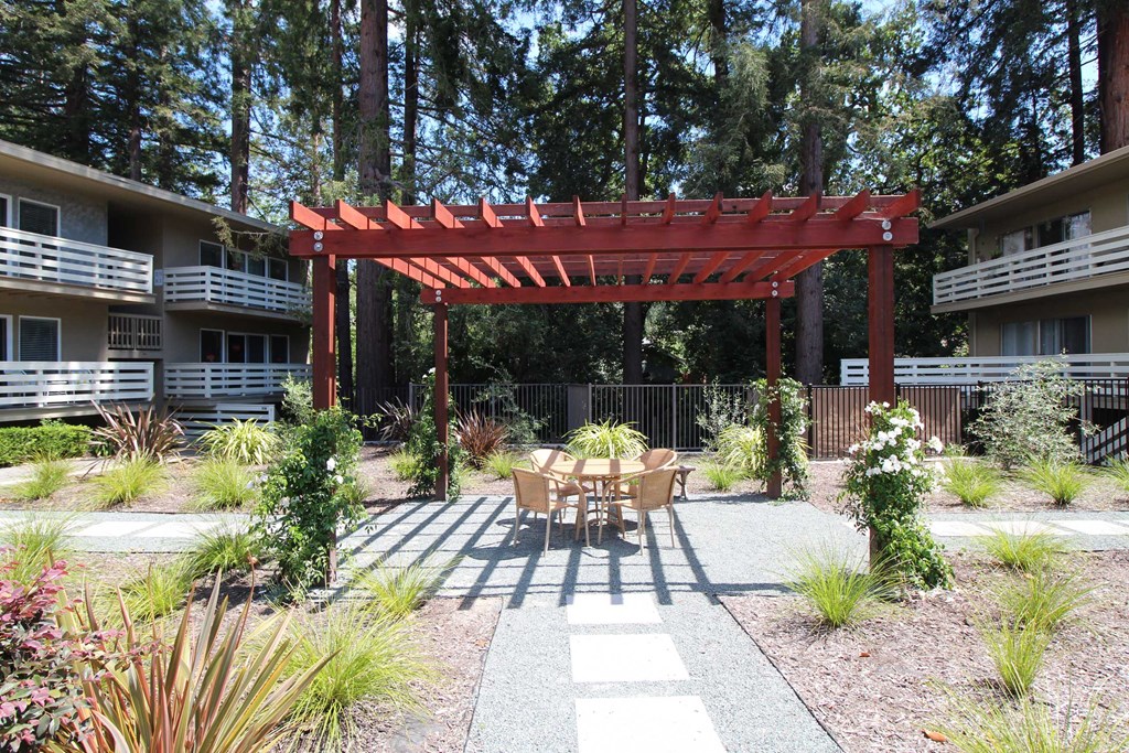 a patio with a table and chairs under a red structure