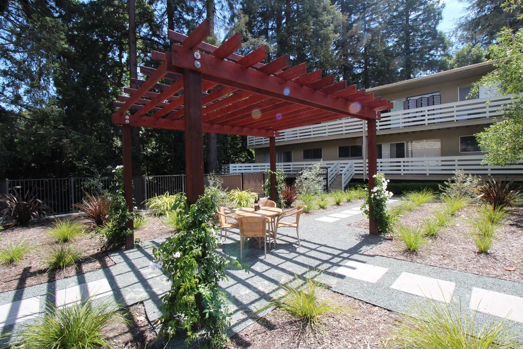 a patio with a table and chairs under a wooden pergola