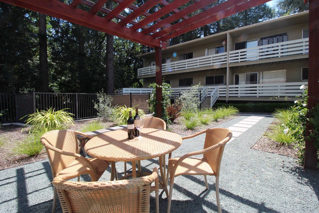 a patio with a table and chairs in front of a building