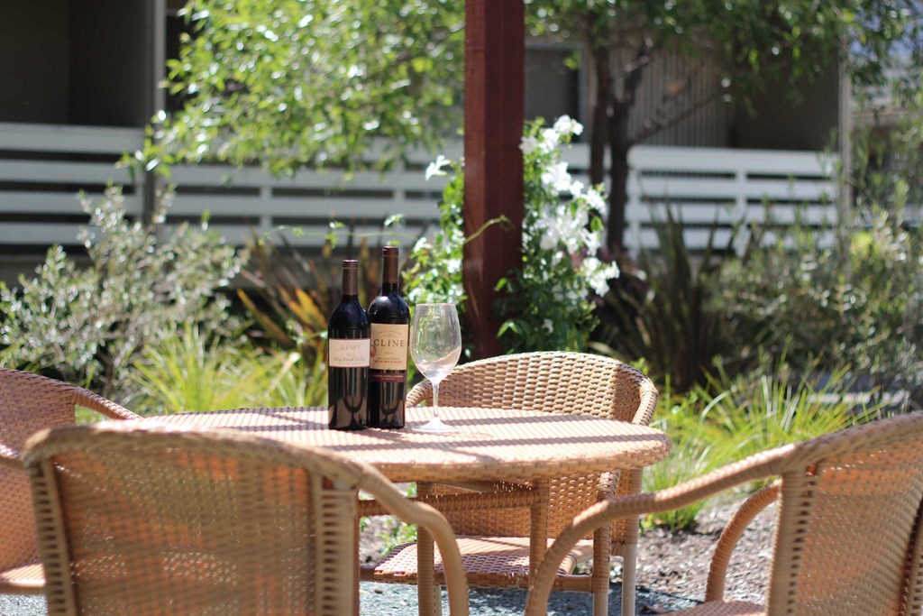 a patio table with two bottles of wine and two wine glasses