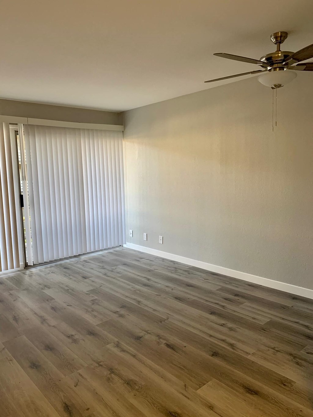 an empty living room with wood flooring and a ceiling fan